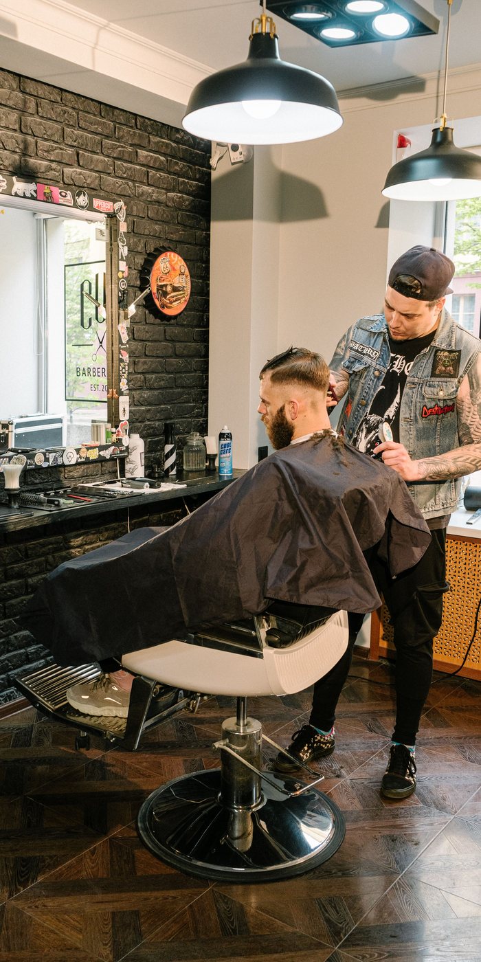 A barber giving a client a haircut in his shop